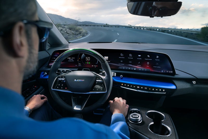 Front View of the 2026 OPTIQ-V Driving Through the Dusk Utilizing its Headlights | Williamson Cadillac in Miami FL