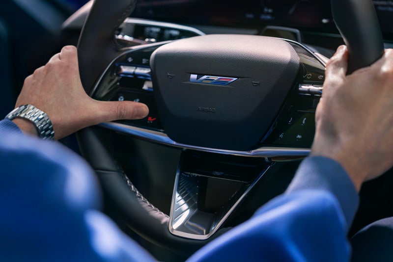 Close-up of a Man About to Press the V-Button on the 2026 OPTIQ-V Steering Wheel | Williamson Cadillac in Miami FL